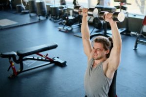 Man shoulder press dumbbells